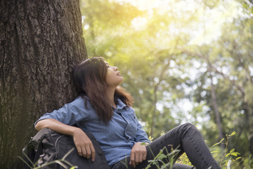 Happy woman enjoy and relax with the nature. Young beautiful woman sitting under the big tree in...