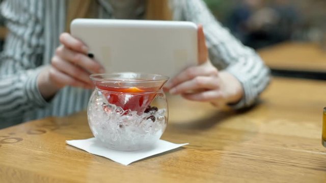 Woman doing photos of facy drink on tablet while sitting in the cafe
