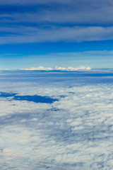 Fototapeta na wymiar 飛行機の窓から見える 雲　青空　陸　