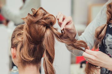 Fototapeta premium High Hairstyle creating process in hairdresser salon with elegant bun. Blonde and red hairs
