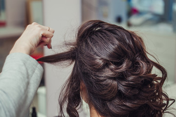 Obraz premium Close-up hairdresser coiffeur makes hairstyle in beauty salon. Barber at work