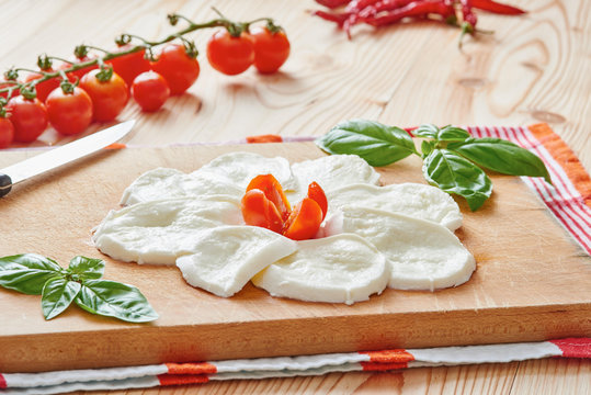 Slices of mozzarella, cherry tomato and fresh basil - ingredients for caprese salad