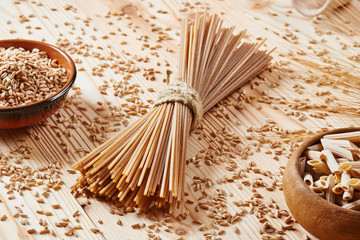 Uncooked whole wheat pasta spaghetti surrounded by wheat