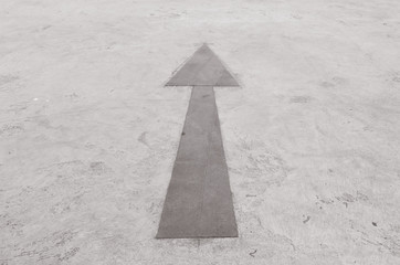 Closeup surface old and pale painted arrow sign on cement street floor textured background in black...