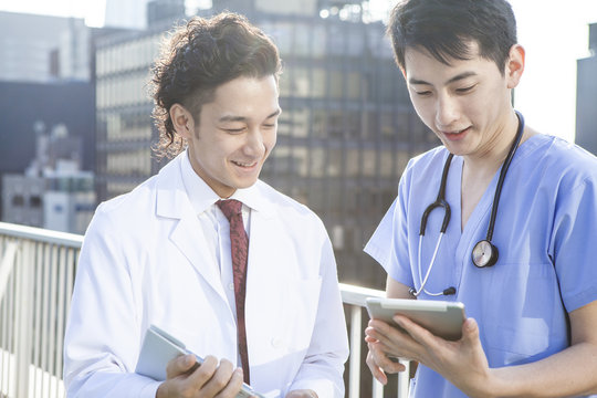 Two young doctors are watching electronic tablet on the hospital's rooftop