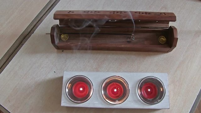 Joss-stick smokes with small candles on a table