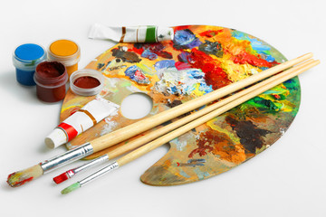 Wooden art palette, gouache  and a brush on white background.