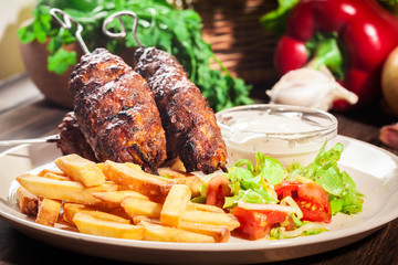 Grilled shish kebab served with fried chips and salad