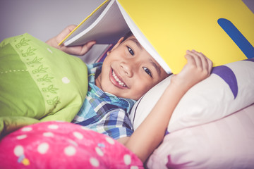 Close up. Asian boy covering head with book and smiling. Education.