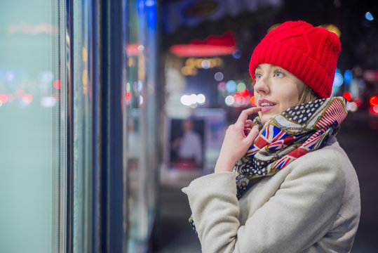 Young woman enjoying window shopping. Woman with red hat looking