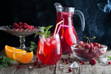 Cocktail of berry juice, orange and peppermint on a wooden background