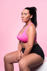 Obraz premium Beautiful plump woman sitting against pink background