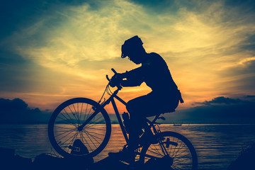 Fototapeta premium Healthy lifestyle. Silhouette of bicyclist riding the bike at seaside