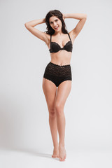 Fototapeta premium Happy brunette woman in lingerie posing with arms raised