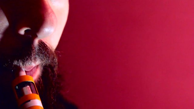 Man with beard vaper smokes vaping closeup