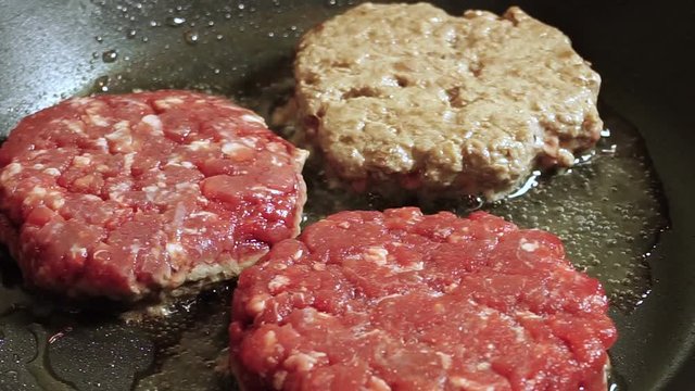 Cooking hamburger. Three beef cutlets for burgers are fried in a frying pan. HD