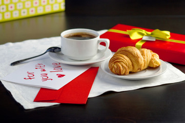 A cup of coffee and a croissant. Festive breakfast Valentine's Day with love letters.