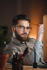 Attractive designer working at night and looking to computer