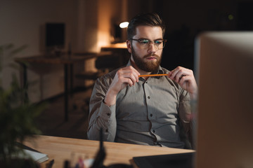 Concentrated bearded web designer working late at night