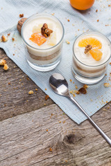 Fresh homemade dessert with biscuits, yogurt, tangerines and walnuts, served in a glass
