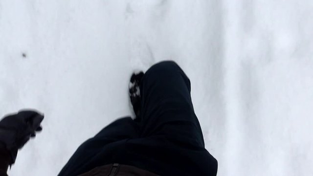 Man goes on snowy road - detail of legs