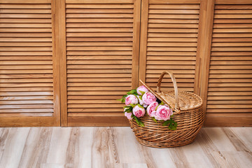 Fototapeta na wymiar Pink flowers in basket on wooden background with free space for text.