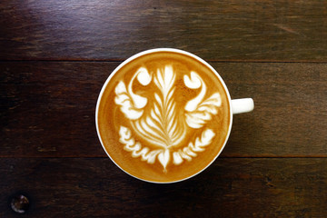 cup of latte art coffee on wooden background