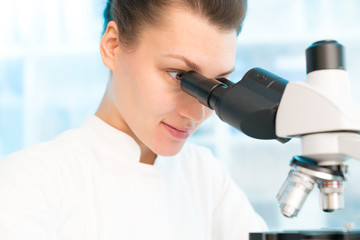 Young woman in biological laboratory with trinocular mivroscope  Attractive young female scientis. Scientist using a microscope in a laboratory