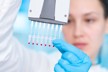 Woman technician with multipipette in genetic laboratory PCR research. Student girl use pipette....