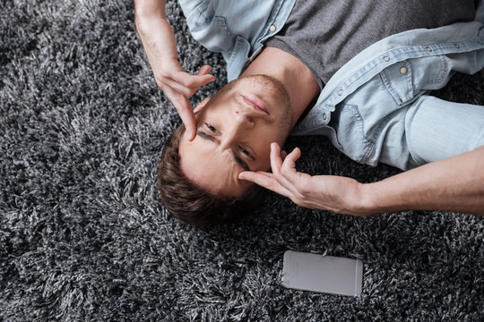 Man lying on a carpet and intensively thinking