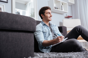 Man making notes in copybook while sitting on the carpet