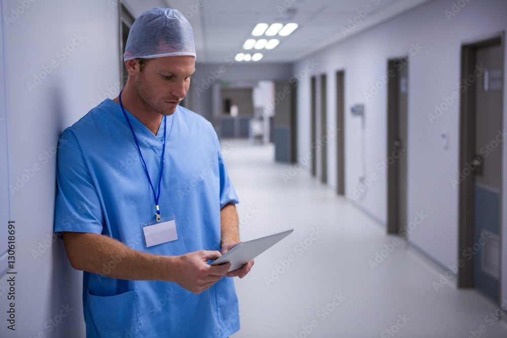 Poster surgeon using digital tablet in corridor