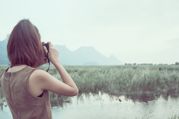 Hipster Traveler with backpack and taking photo of amazing lands