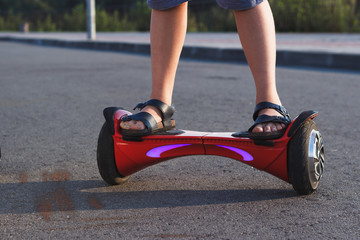 Boy stands on a red gyro scooter, outdoors