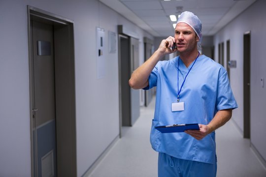 Surgeon standing in corridor and talking on mobile phone