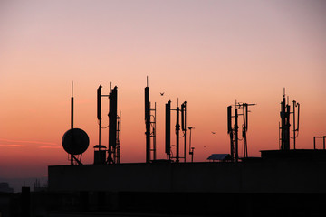 silhouette of GSM transmitters on the roof office building at dusk