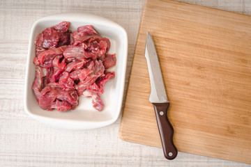 Sliced raw meat with knife on the white table top view