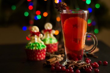 Christmas decoration. Cup of mulled wine and christmas cupcakes on bokeh background. Selective focus