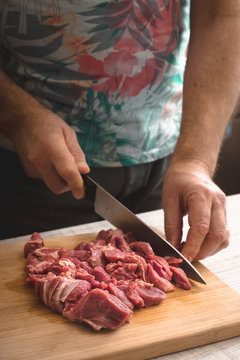 Cutting raw meat on the wooden board vertical