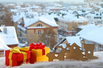 Рождественские и новогодние декорации из дерева на фоне зимнего городского пейзажа. - obrazy, fototapety, plakaty