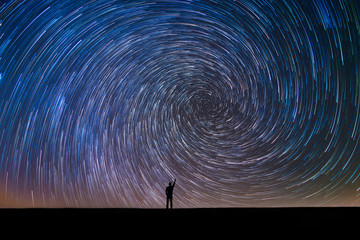 Silhouette of a man pointing at the north star vortex star trail  - obrazy, fototapety, plakaty