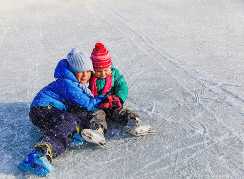 happy little boy and girl learning to skate in winter