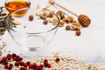 Cereal and various delicious ingredients around empty plate for breakfast on white background. Top view.