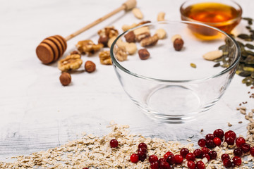 Cereal and various delicious ingredients around empty plate for breakfast on white background. Top...