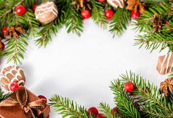 Fototapeta na wymiar Christmas frame with green spruce twigs, holly and chocolates