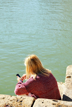 Blonde woman talking on the phone on the dock port