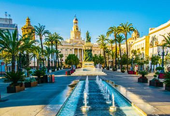 View of a fountain situated on the square of saint john of god in cadiz with town hall on background - obrazy, fototapety, plakaty