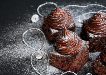 Brownie cake bites with chocolate cream and berries - dessert idea for holiday party on dark Christmas background, blank space for recipe text