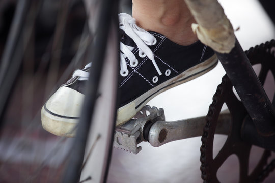 Person riding a vintage bicycle, close up view of sneaker shoe a