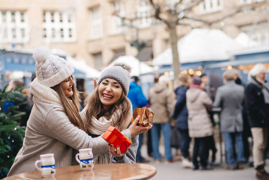 two girls best friends giving presents on christmas market